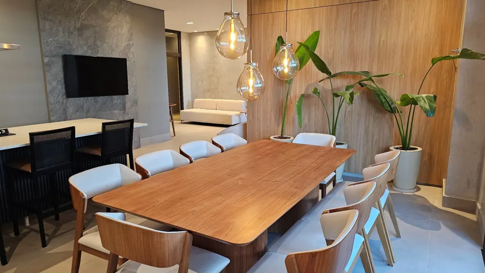 Ambiente social com mesa ampla e cozinha